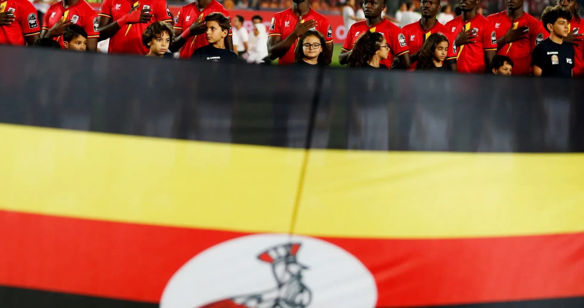 Ugandan team standing during national anthem with flag