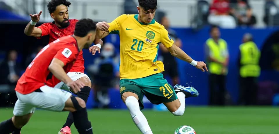 Australia player attempting to dribble past Egypt opponents
