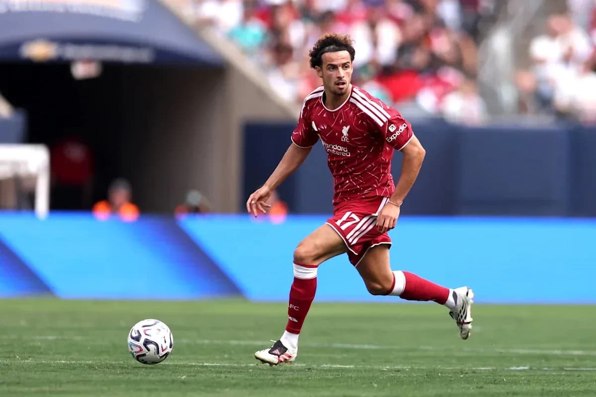 Player in red Liverpool kit dribbling ball on field