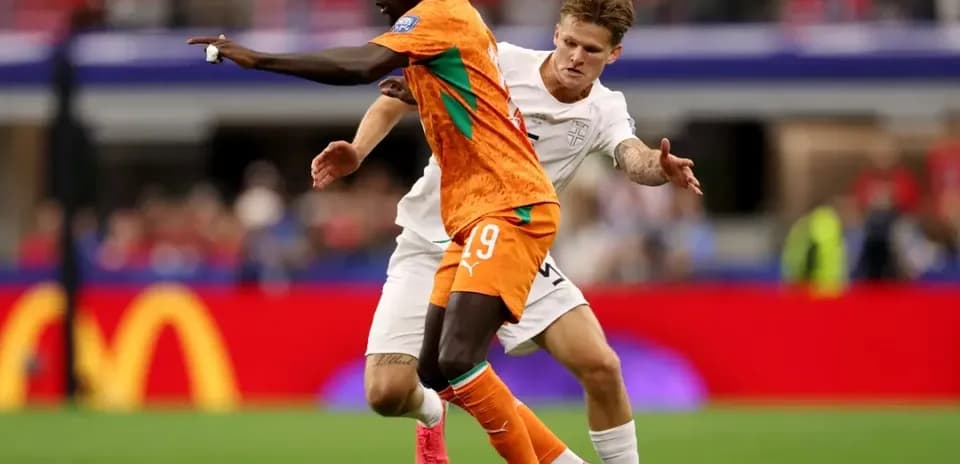 Player in orange shirt dribbling past opponent in white