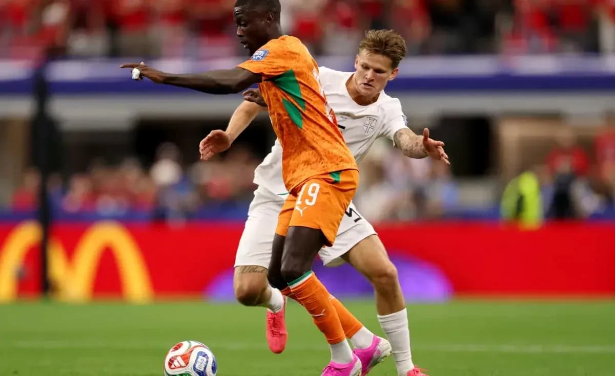 Player in orange shirt dribbling past opponent in white