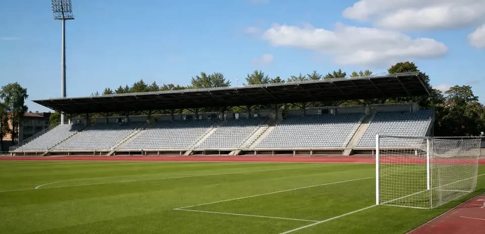 Empty football stadium with green pitch and stands