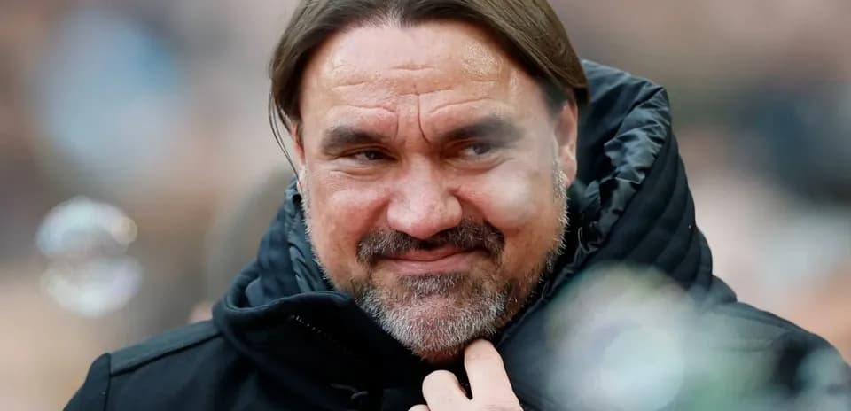 Coach wearing a black jacket, smiling subtly
