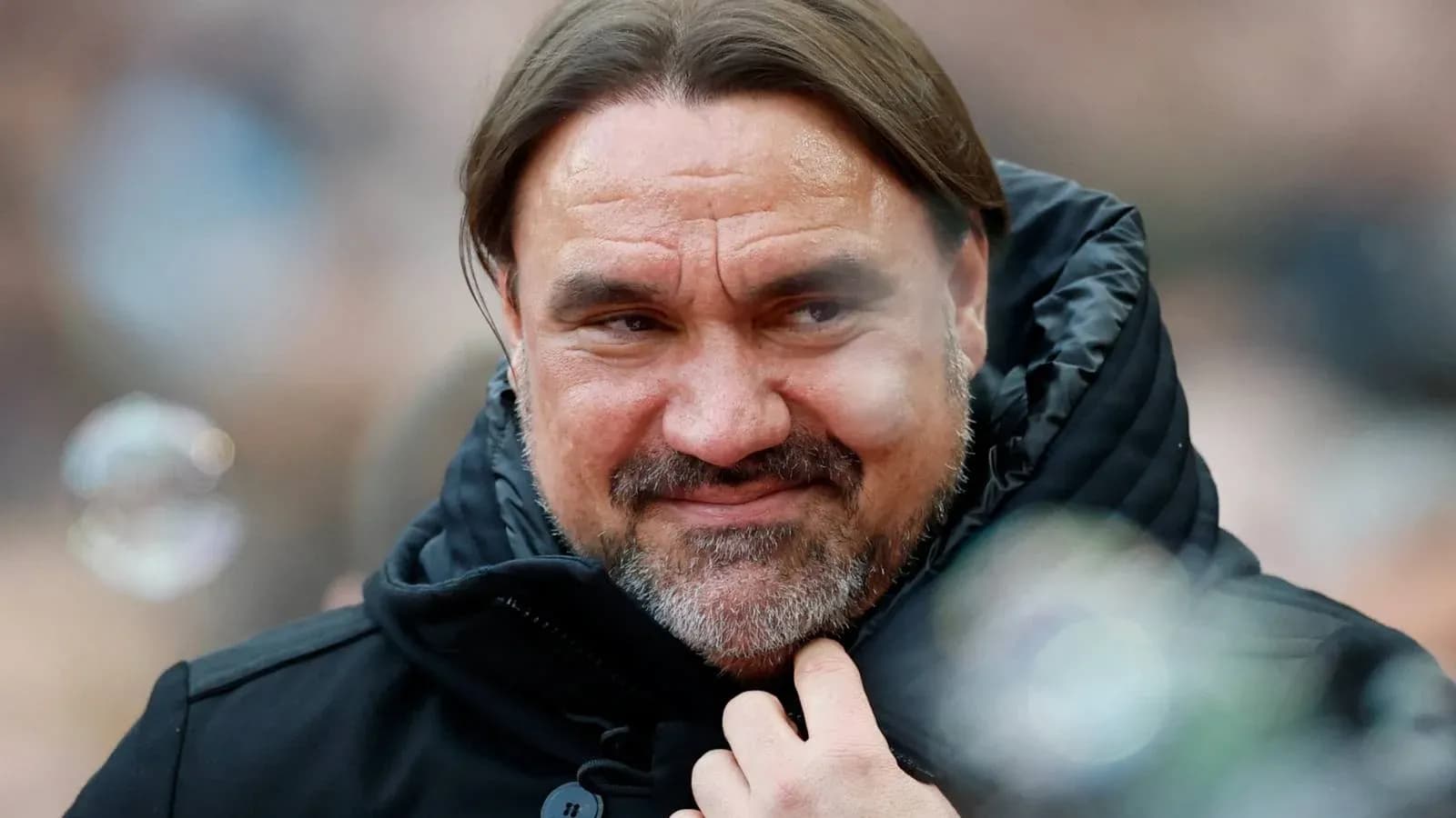 Coach wearing a black jacket, smiling subtly