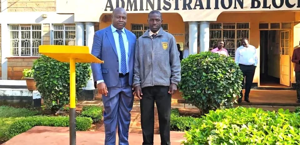 Two individuals posing in front of school administration block