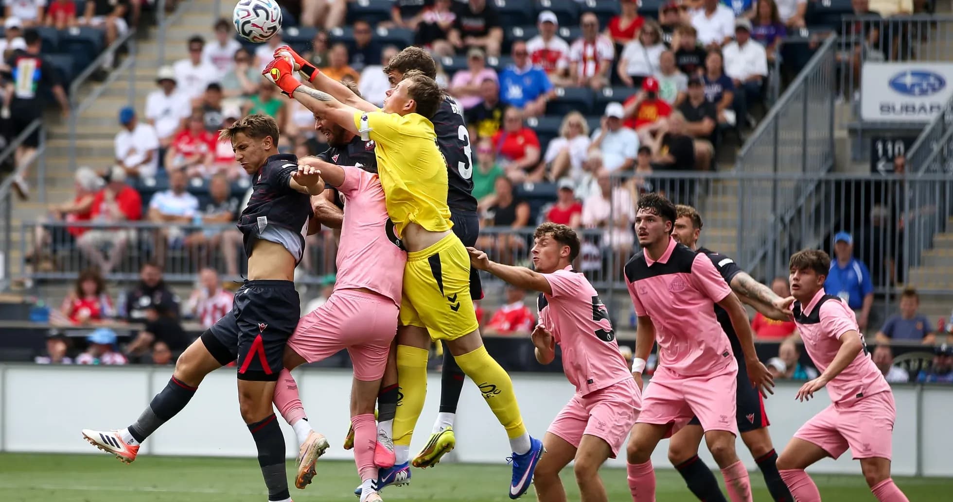 Goalkeeper jumping to catch the ball amidst players