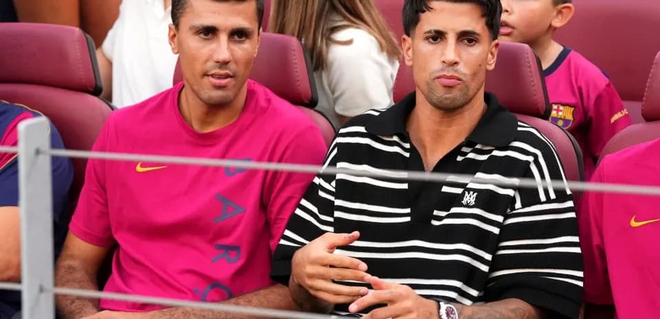 Two men seated in stadium wearing Barcelona jerseys