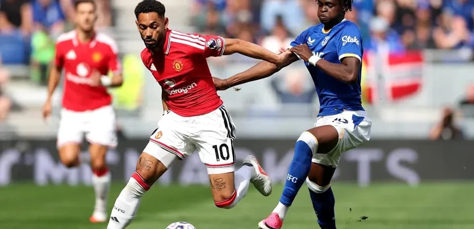 Manchester United player dribbling past Everton defender