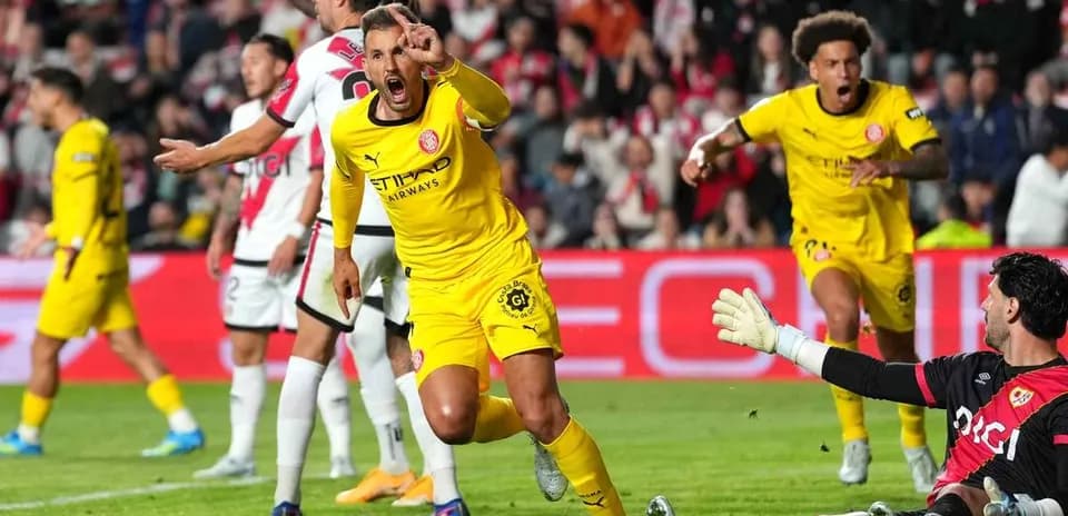 Player celebrating a goal while goalkeeper reacts