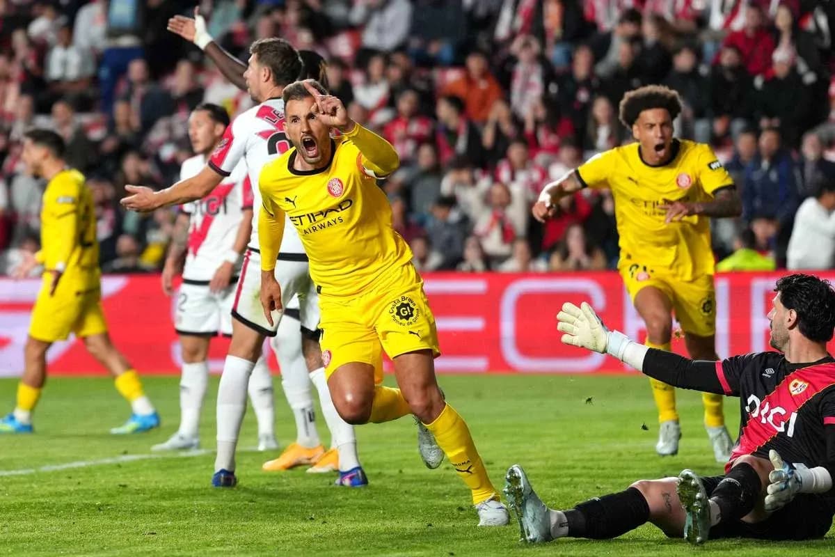Player celebrating a goal while goalkeeper reacts