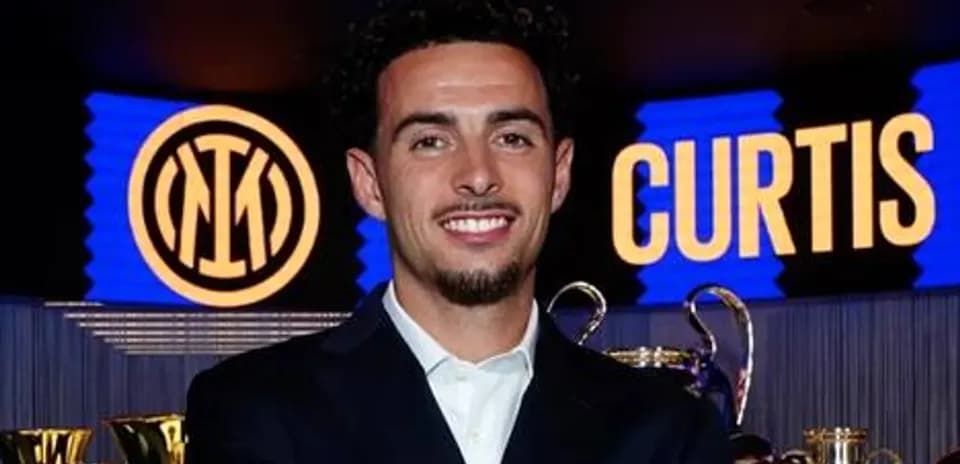 Player smiling in front of trophies and logo