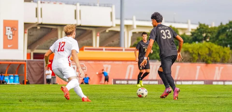 Player in white jersey chasing ball held by opponent