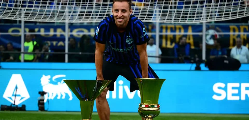 Player posing with two trophies on the field