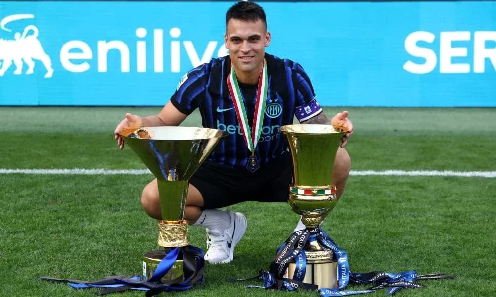 Player celebrating with two trophies on the field