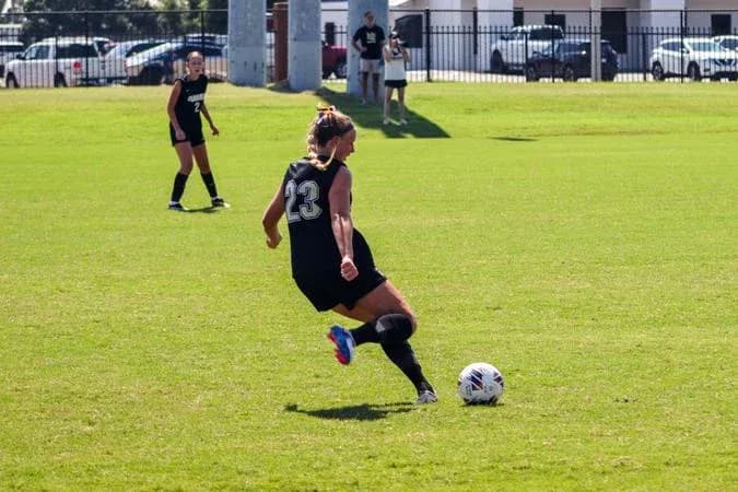 Player number 23 kicking a soccer ball on field