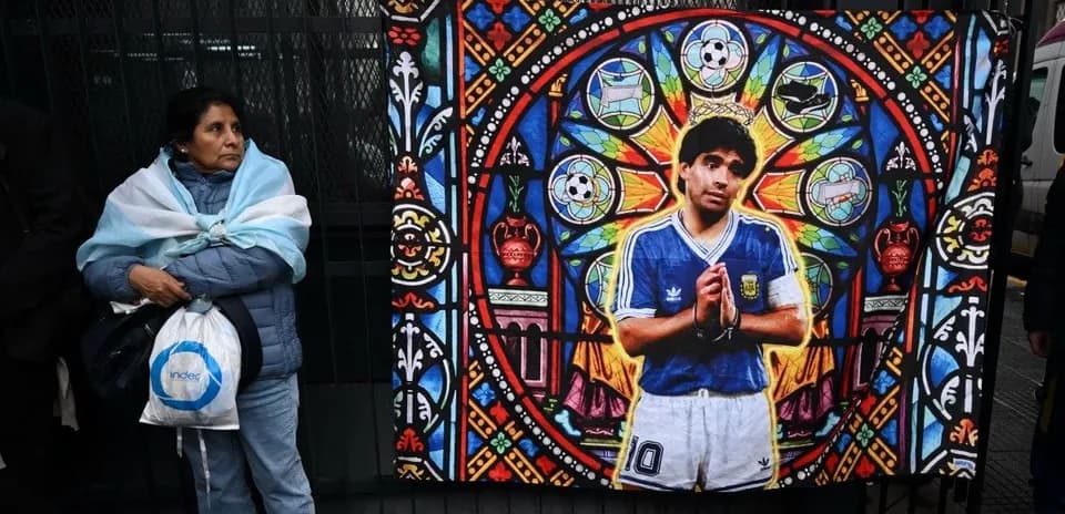 Woman standing next to mural of Diego Maradona