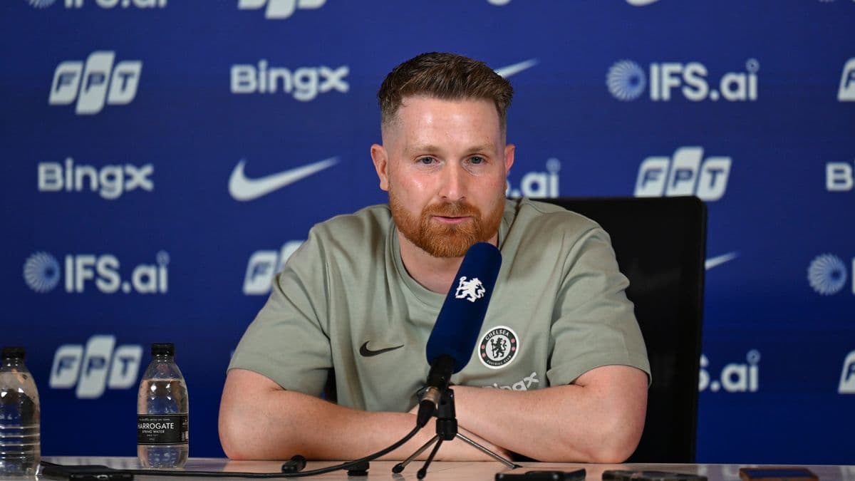 Manager speaking at press conference with sponsors backdrop