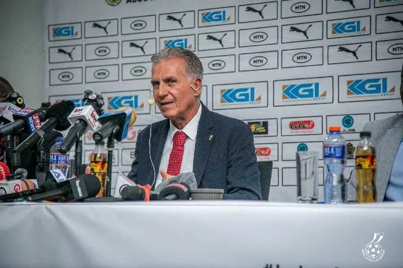 Coach speaking at press conference with microphones
