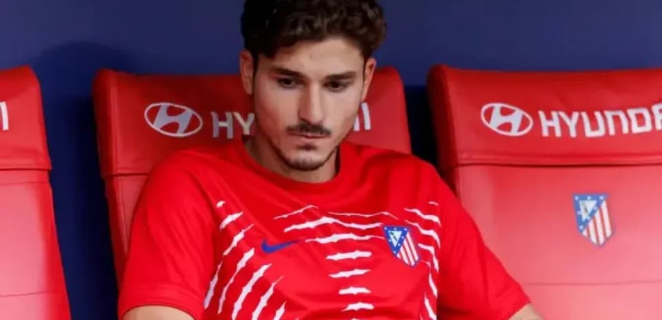 Player sitting on bench in red Atlético Madrid kit