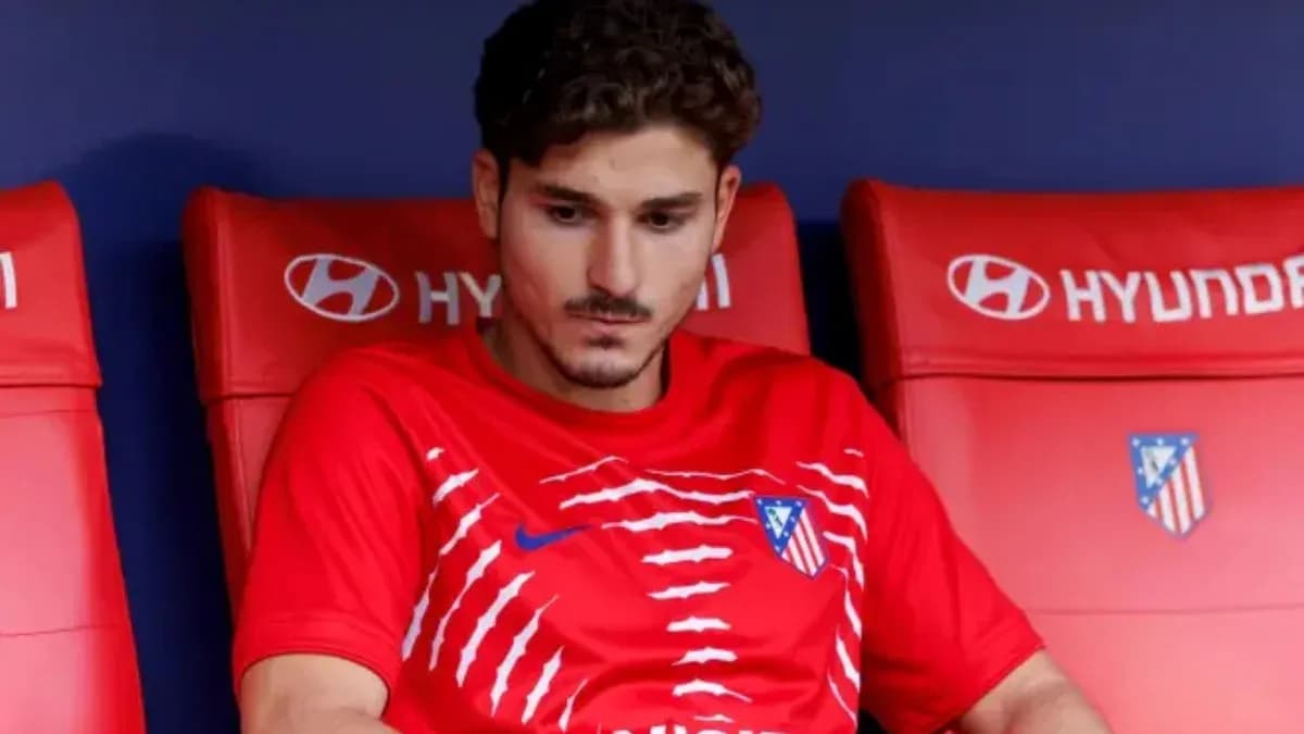 Player sitting on bench in red Atlético Madrid kit