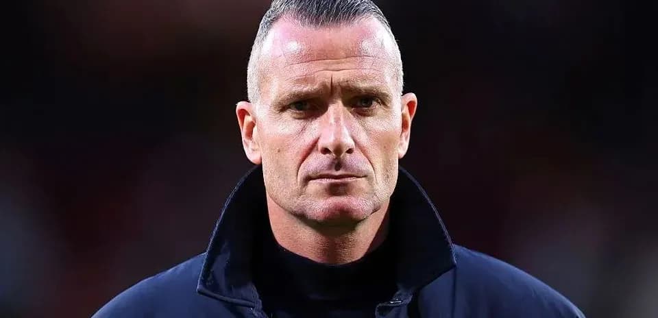 Coach standing with serious expression on sidelines