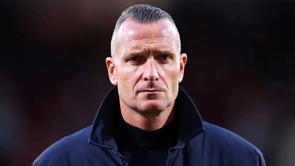 Coach standing with serious expression on sidelines
