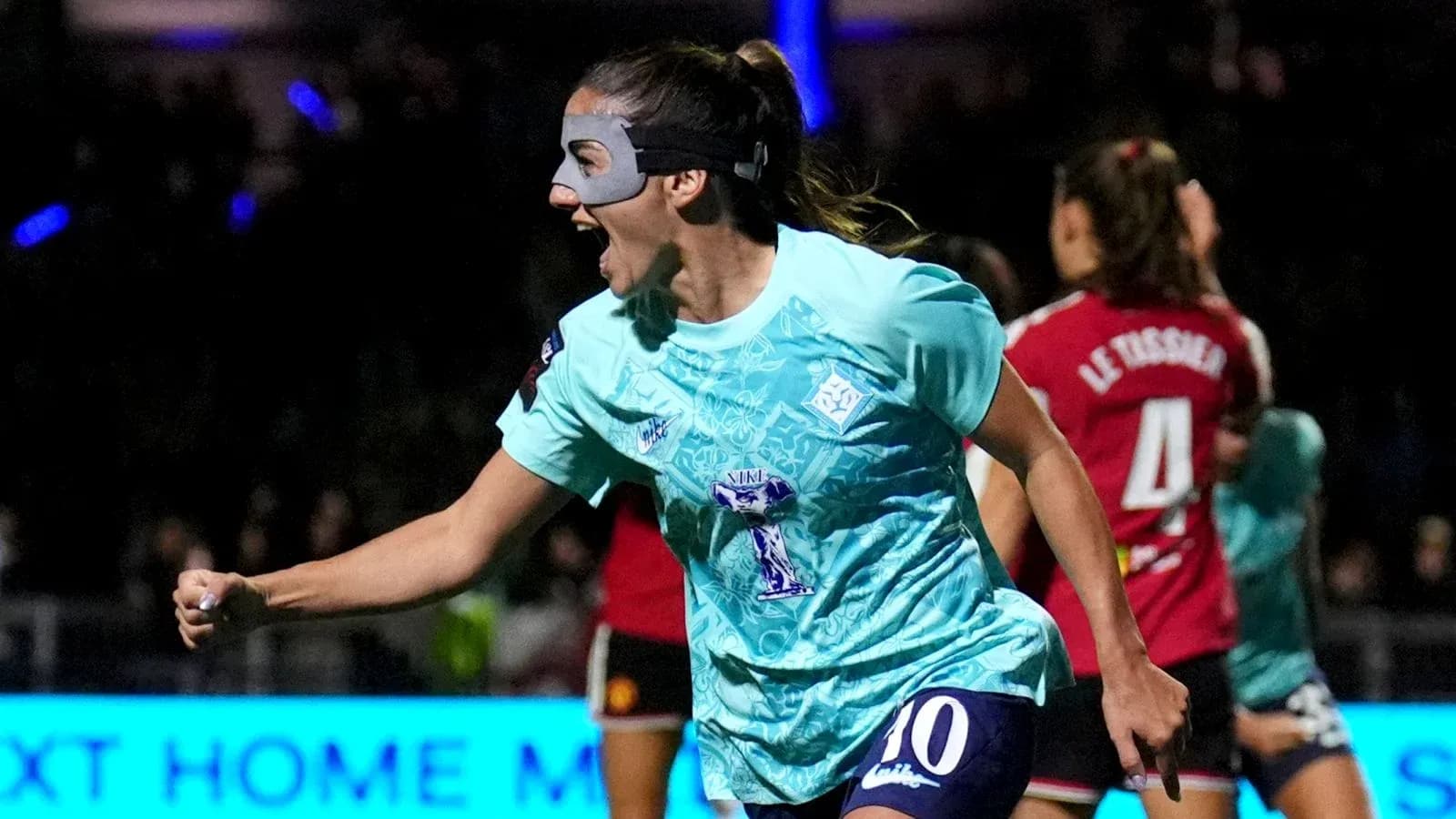 Player celebrating a goal wearing a mask