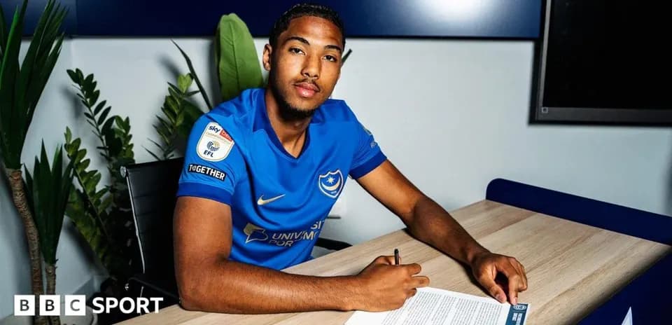Player signing contract at desk in club jersey