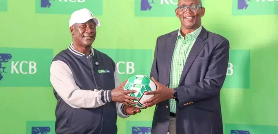 Two individuals holding a soccer ball at KCB event