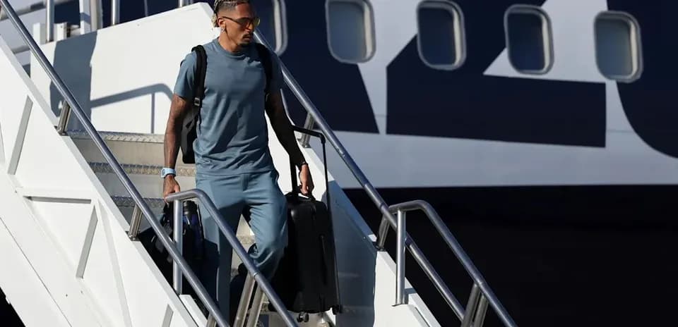 Player disembarking from airplane with luggage