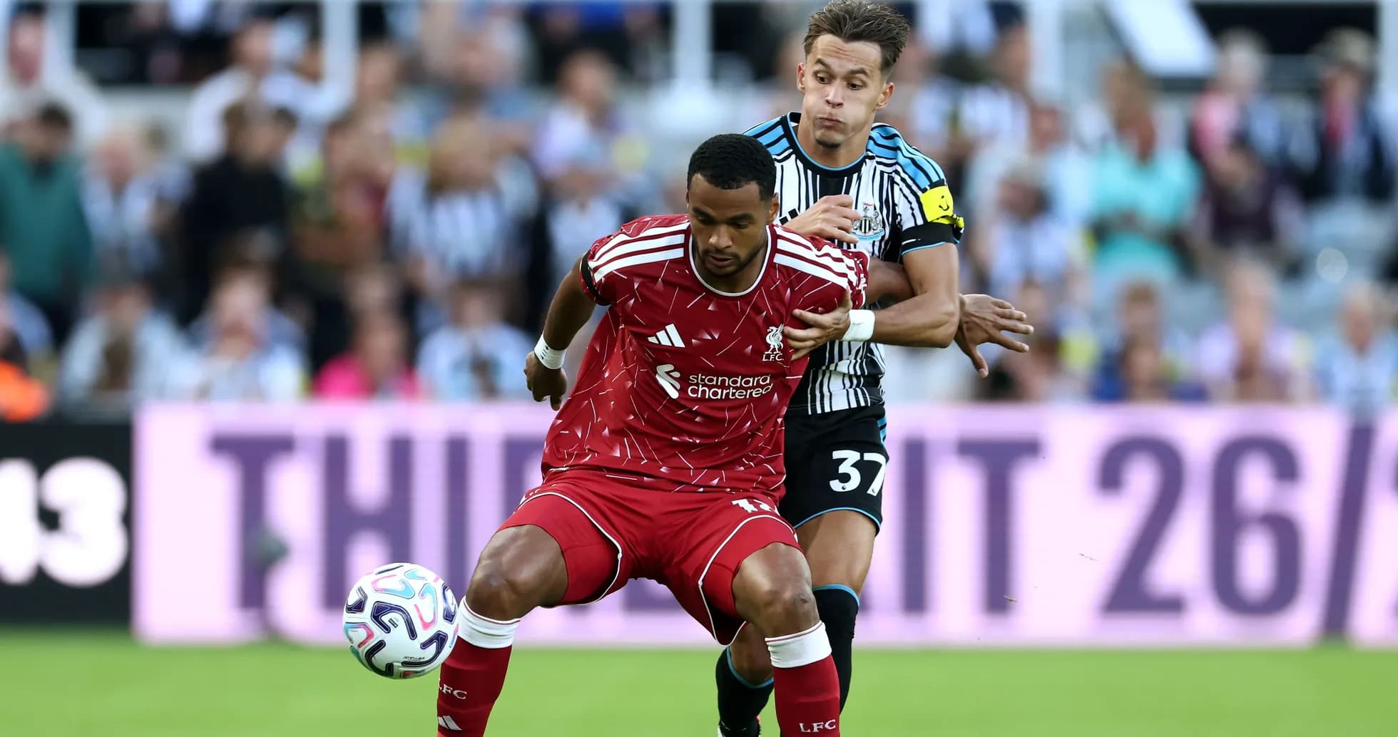 Liverpool player dribbling while Newcastle player defends