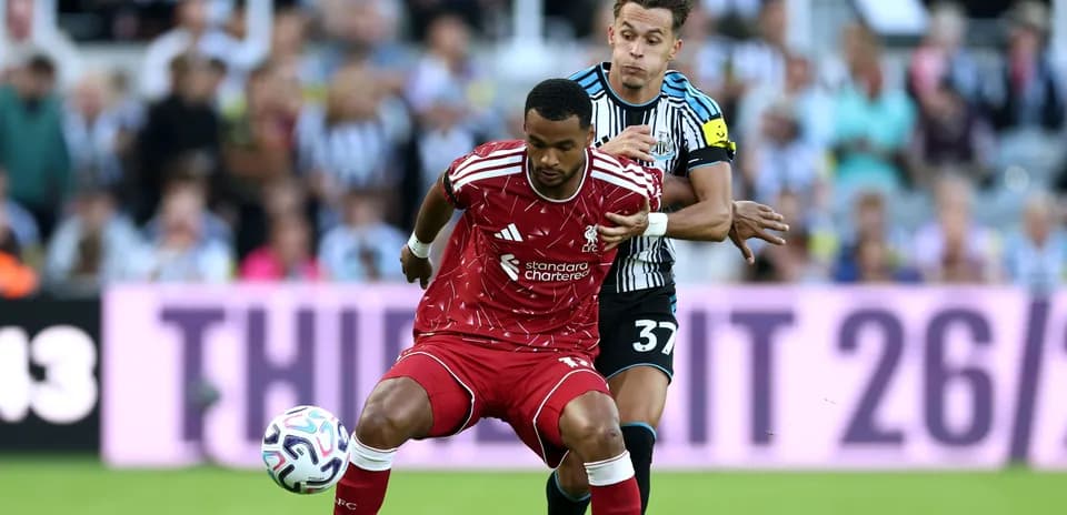 Liverpool player dribbling while Newcastle player defends