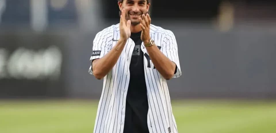 Man in Yankees jersey clapping on field