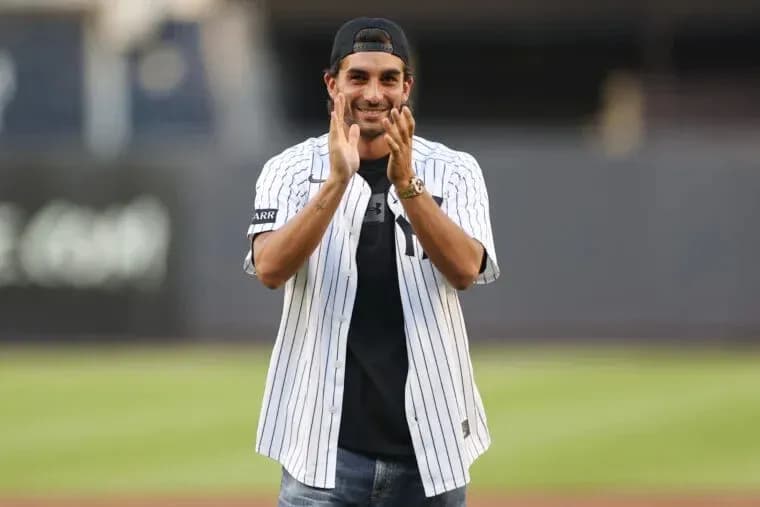 Man in Yankees jersey clapping on field