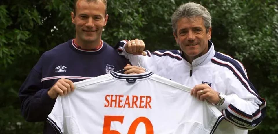 Two men holding an England football shirt with 'SHEARER 50'