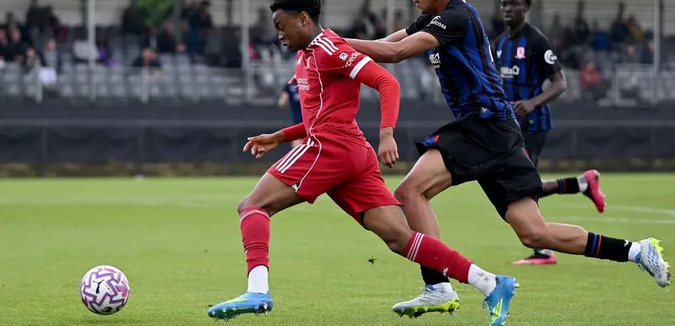 Player in red dribbling while being challenged by opponent