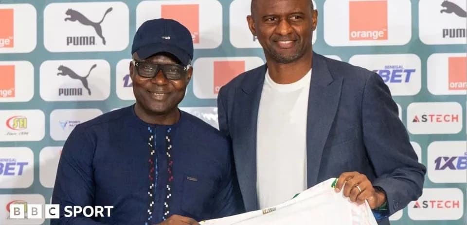 Two men holding a football shirt at press conference