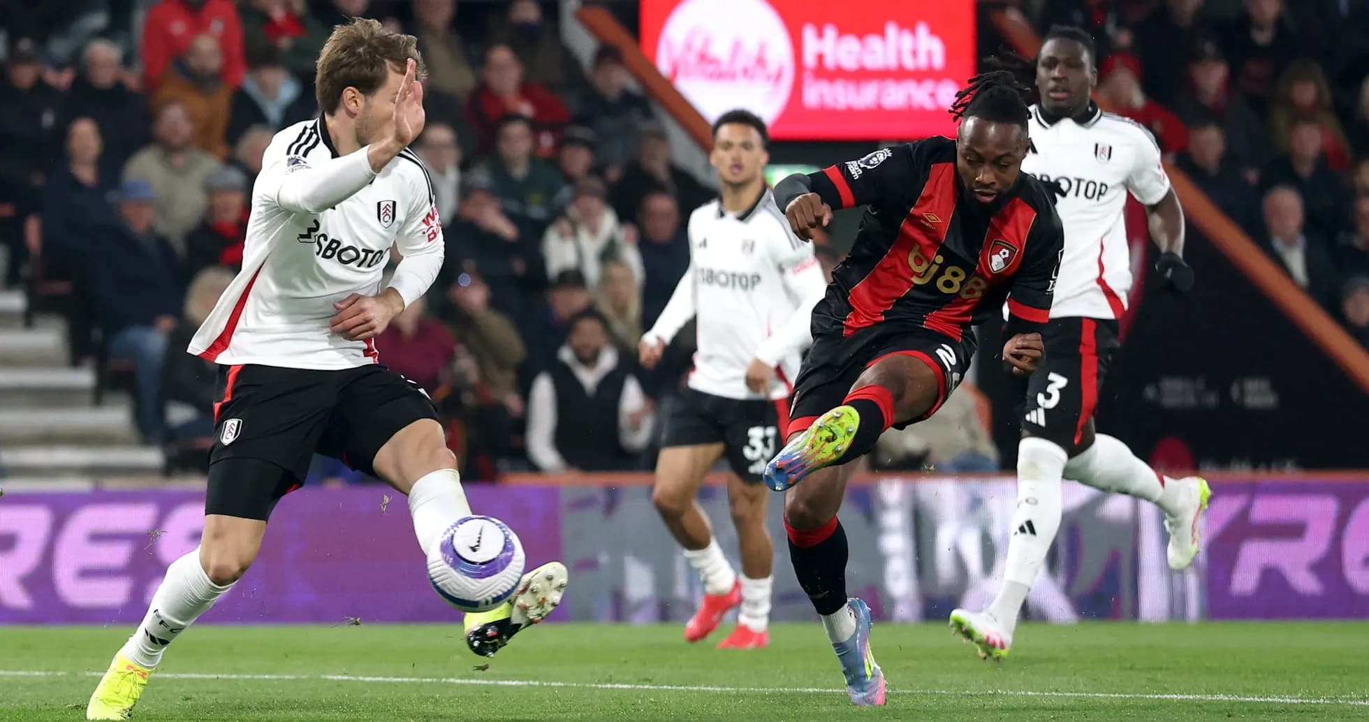 Fulham player challenging Bournemouth player for the ball
