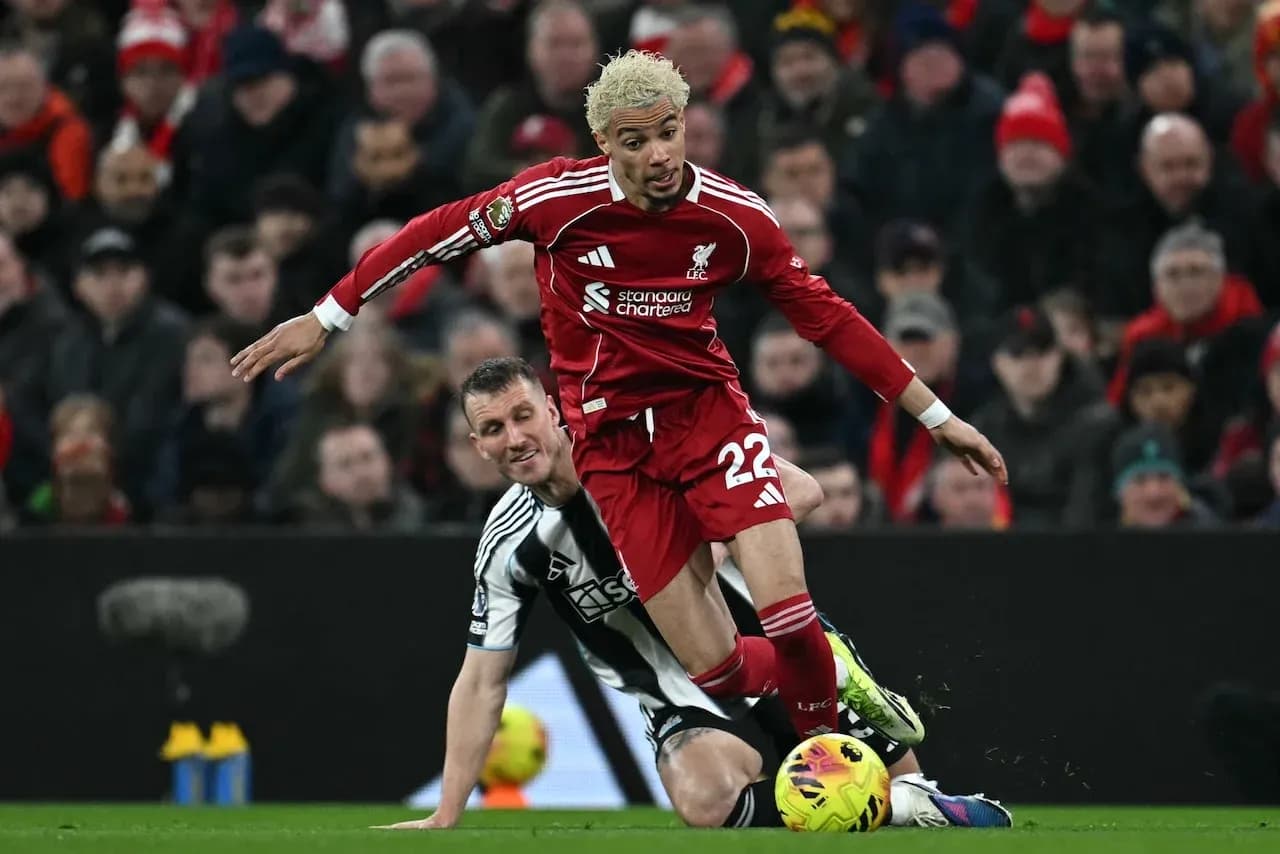 Liverpool player challenging Newcastle opponent for the ball