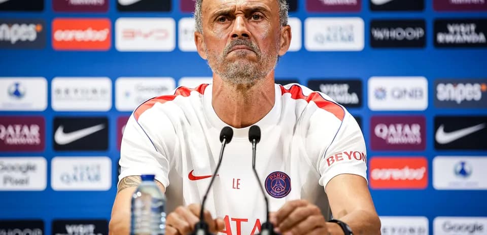 Manager at press conference with sponsor logos in background