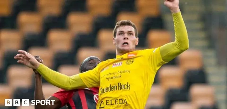 Player in yellow jersey challenges opponent for the ball