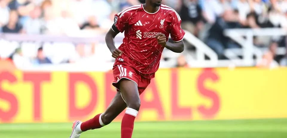 Player running in red Liverpool kit on field
