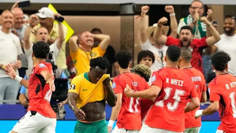 Players celebrating a goal with fans in the background