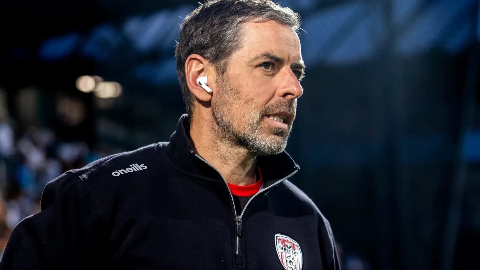 Coach wearing earbuds, focused on the game