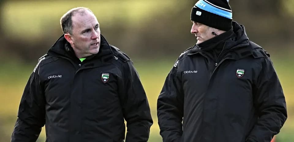 Two coaches discussing strategies on training pitch