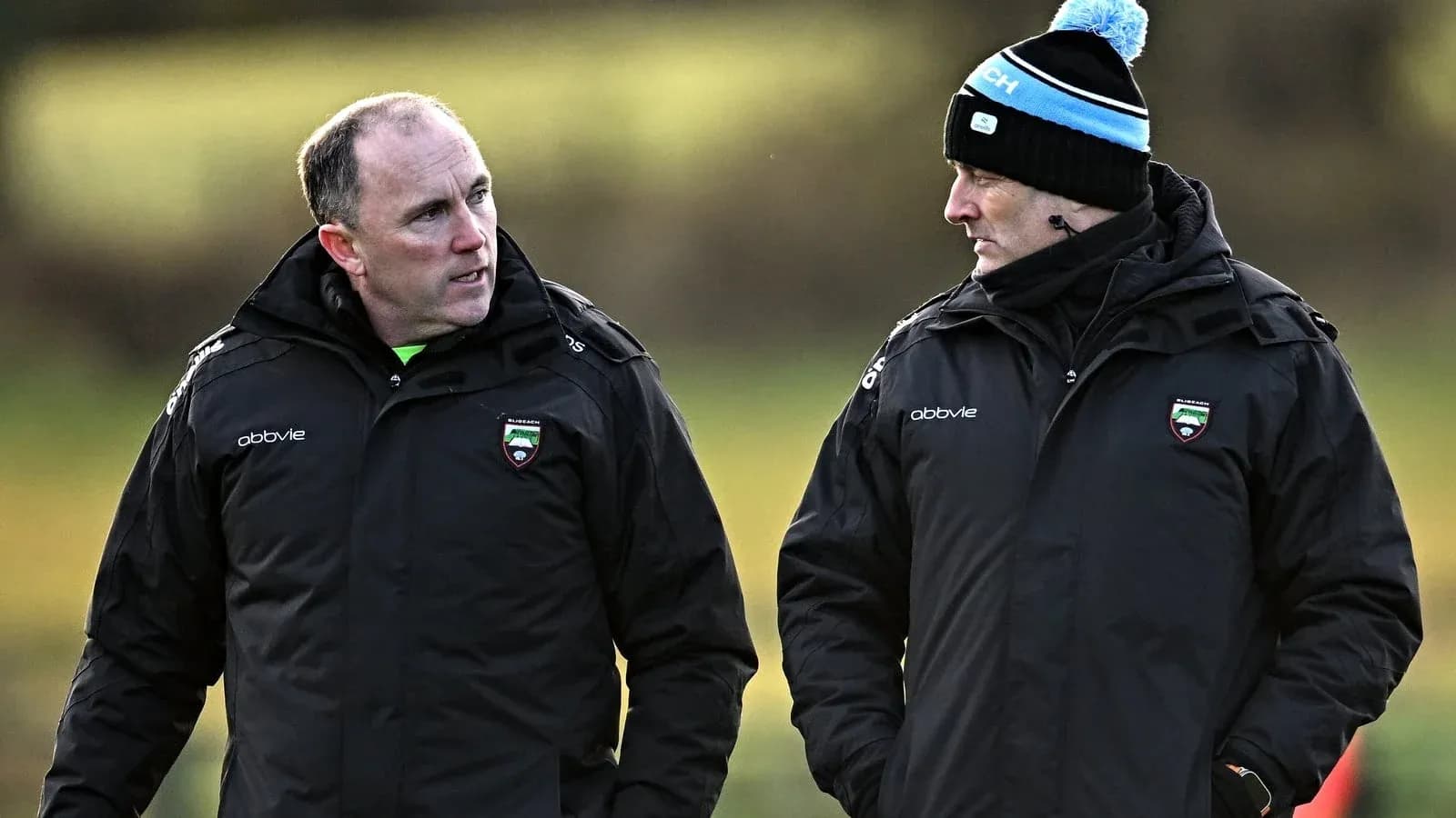 Two coaches discussing strategies on training pitch