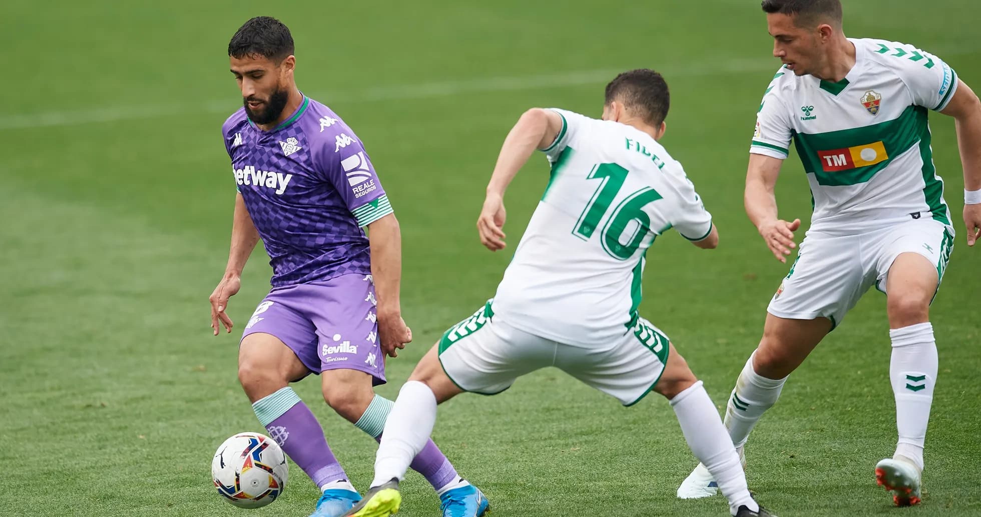 Real Betis player dribbling past Elche defenders