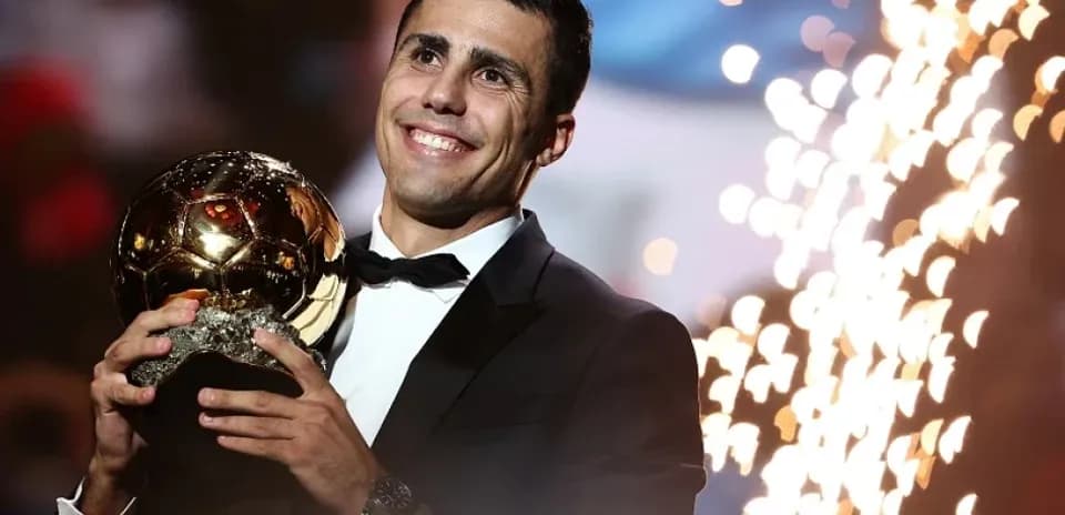 Player holding Ballon d'Or trophy on stage