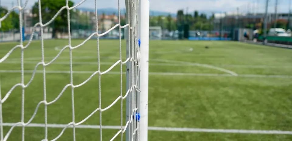 Goal net with football pitch in background