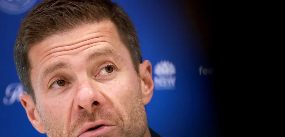 Coach speaking at press conference with blue background